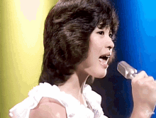 a woman singing into a microphone with syrup written on the bottom left