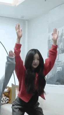 a woman in a red sweater is dancing with her hands in the air .