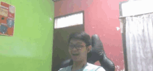 a man wearing glasses is sitting in a chair in a room with a green wall .