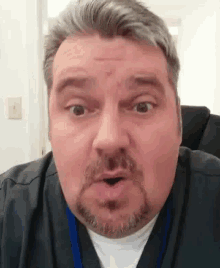 a man with a beard is making a funny face while wearing a scrub top .
