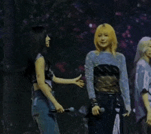 two women are standing next to each other on a stage with microphones in their hands .