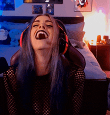 a woman with blue hair and headphones is laughing with her mouth open