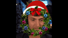 a man is wearing a santa hat and a christmas wreath on his face