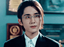 a man with long hair wearing glasses and a suit