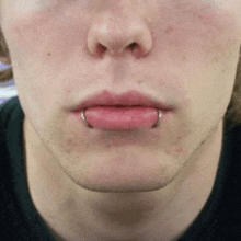 a close up of a man 's face with a lip piercing
