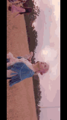 a woman with pink hair is standing in a field of tall grass .