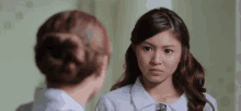 two women are looking at each other in a mirror and one is making a funny face .