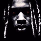 a close up of a man 's face with red eyes and dreadlocks