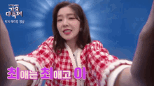 a woman in a red and white plaid dress is holding her arms up in front of a blue background that says kbs