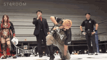 a man kneeling down in a wrestling ring with stardom in the background