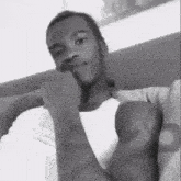 a black and white photo of a man with his hand on his chin .