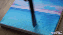a blue and pink painting is being painted on a canvas