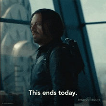 a man in a black leather jacket is standing in front of a window and says this ends today .