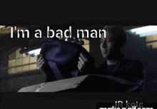 a man in a suit is holding a purple bag and the words i 'm a bad man are above him