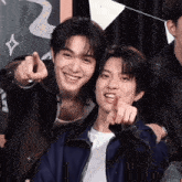 two young men pointing at the camera and smiling