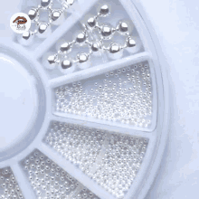 a white nail with pearls and rhinestones has nails written on the bottom right