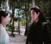 a man and woman are looking at each other in a forest