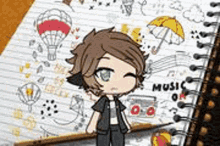a boy is standing in front of a notebook with a drawing of a boy on it .