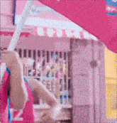 a woman in a pink dress is holding a pink umbrella in front of a store