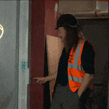 a man wearing a hard hat and an orange vest with the word ic on it