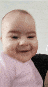 a baby is smiling and looking at the camera