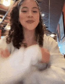 a woman with curly hair is wearing a white shirt and smiling