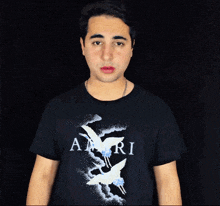 a man wearing a black shirt with the word amiri on the front