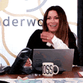 a woman sits at a desk with a laptop and a mug that says boss on it