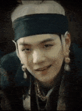 a close up of a person wearing a headband , earrings , and a necklace .