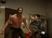 a man without a shirt is standing in a room with a sword