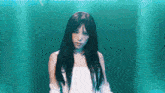 a young woman with long black hair is standing in front of a blue background .