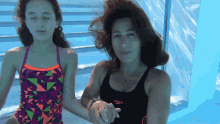 a woman in a speedo tank top holds hands with a girl