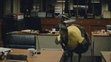 an ostrich in a yellow shirt is standing in front of a desk with a name plate that says lime