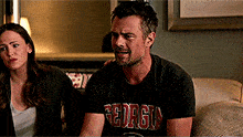 a man wearing a georgia shirt sits on a couch with a woman