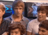 a group of young men are standing in front of a television screen .