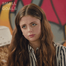 a woman with long hair is wearing a striped shirt with the words small achievable goals on the bottom right