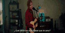 a man in a plaid shirt is singing into a microphone while playing an acoustic guitar .