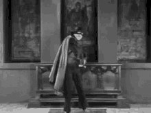 a black and white photo of a man in a costume standing in front of a painting .