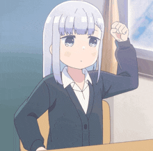 a girl with white hair is sitting in a classroom with her fist in the air
