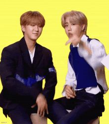two young men are sitting next to each other and one is pointing at the camera