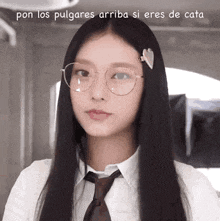a woman wearing glasses and a tie is looking at the camera with a caption in spanish .
