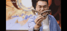 a man wearing glasses is holding a piece of wood in his hands