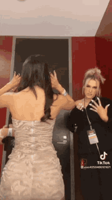 a woman in a dress is standing next to another woman in a black shirt .