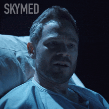 a man is laying in a hospital bed with the word skymed above him