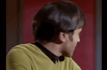 a man wearing a yellow sweater and a black shirt is smiling and looking at the camera .