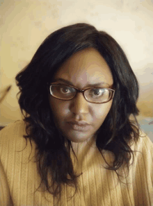 a woman wearing glasses and a sweater looks angry