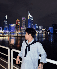 a young man with a tattoo on his arm stands in front of a city skyline