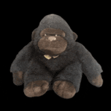 a stuffed gorilla with a bow tie is sitting on a black surface