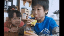 a boy and a girl are drinking orange juice through a straw .