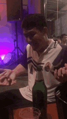 a man sitting at a table with a bottle of beer in front of him